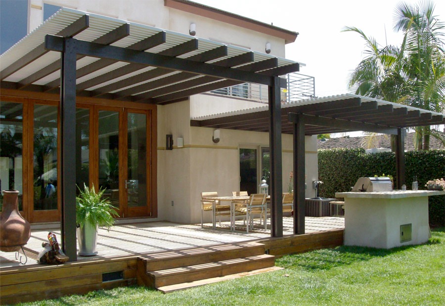 A patio area with a pergola and a BBQ grill