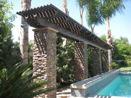 A tranquil swimming pool area with palm trees and a pergola providing shade