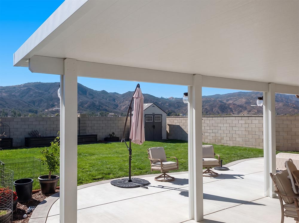 White non-insulated solid aluminum patio cover with three post lights overlooking the Elsinore Valley hills