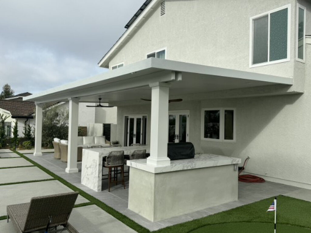 White solid aluminum patio cover with a marble outdoor kitchen bar and putting green in Lake Forest, CA