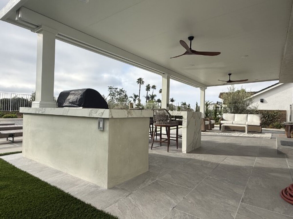 Built-in barbecue island and bar seating under a solid aluminum patio cover in Lake Forest, CA