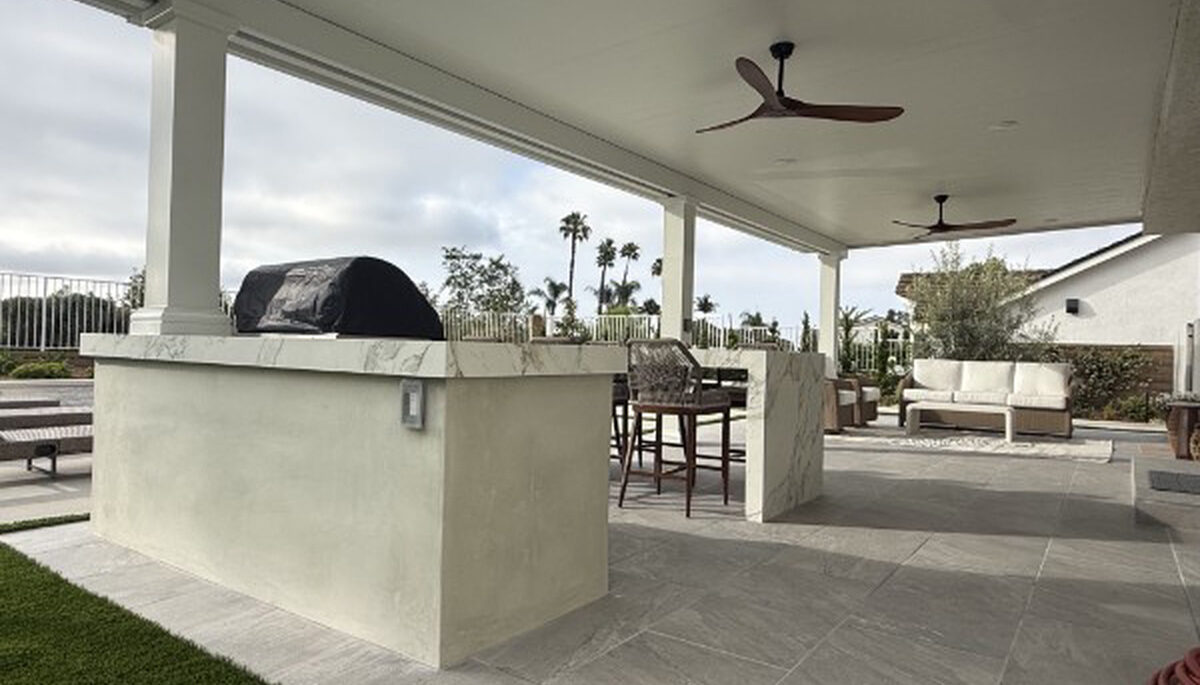 Built-in barbecue island and bar seating under a solid aluminum patio cover in Lake Forest, CA