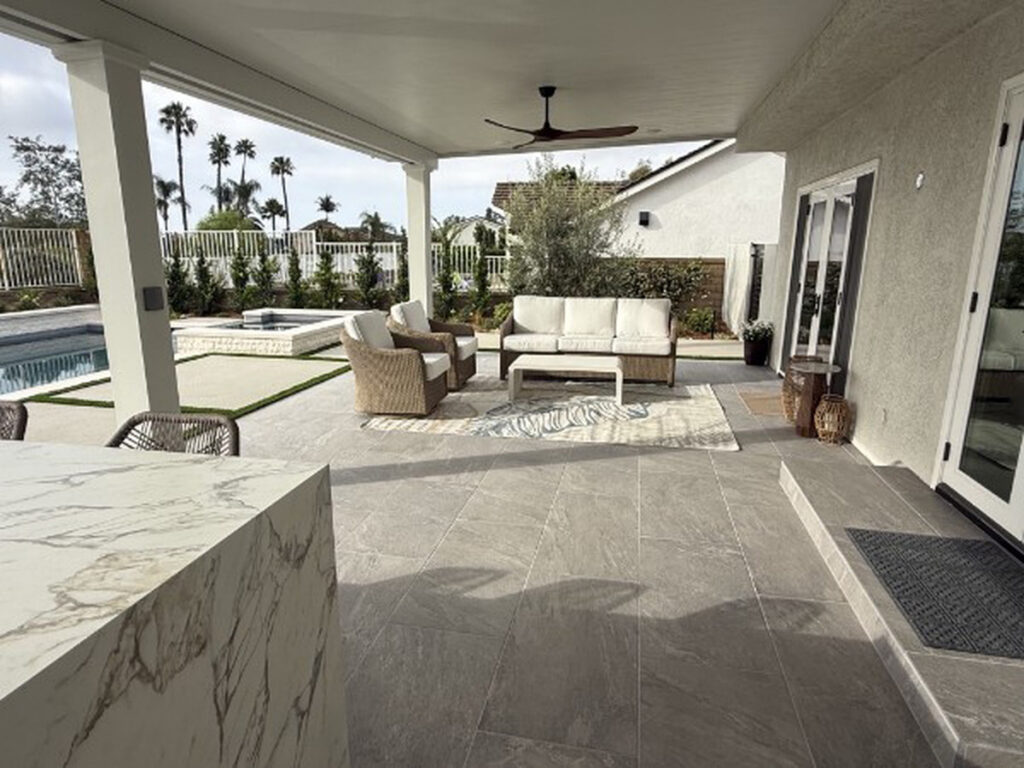Covered outdoor lounge and marble island beneath a solid aluminum patio cover in Lake Forest, CA