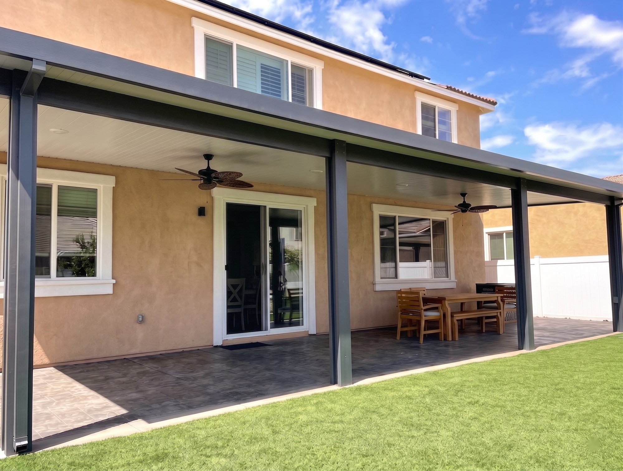 Dark frame and light ceiling on a solid patio cover against tan stucco.